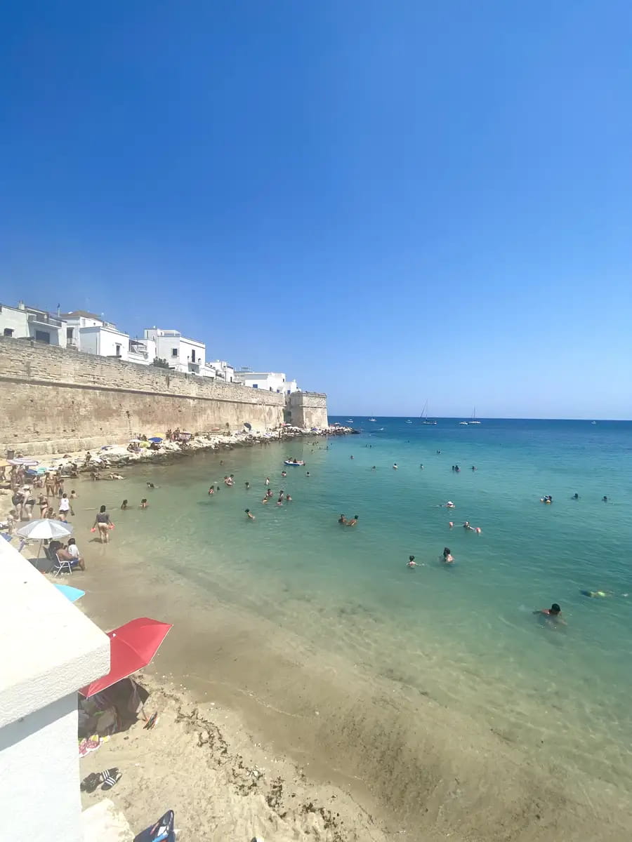 sandy Cala Porta Vecchia Beach with people swimming in the turquoise sea