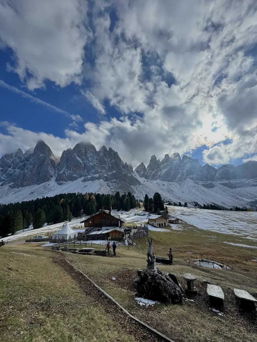 view of the odle mountains from Geisler Alm wooden sunbeds with clouds inbetween