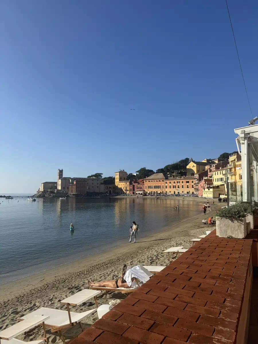 pastel colourful buildings in the baia del silenzio in october people on sunbeds and in the sea