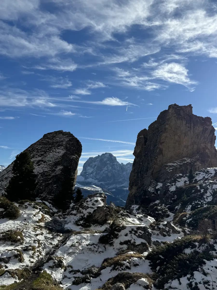 The jagged Pieralongia Twin Spires in the Dolomites with the Sassolungo mountain peak framed perfectly in the middle under a blue sky