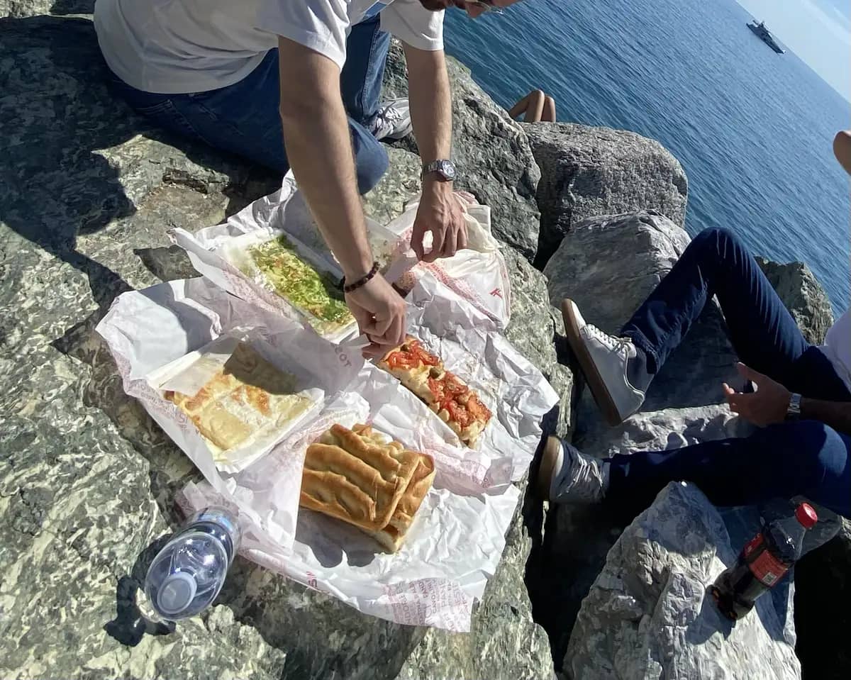 sitting on the rocks at recco beach eating focaccia