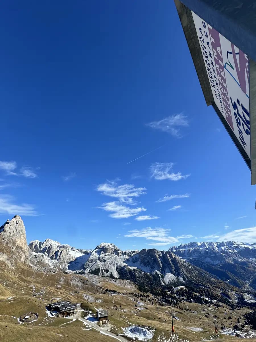 view of val gardena valley on the top of seceda with the apre ski sign and mountain huts