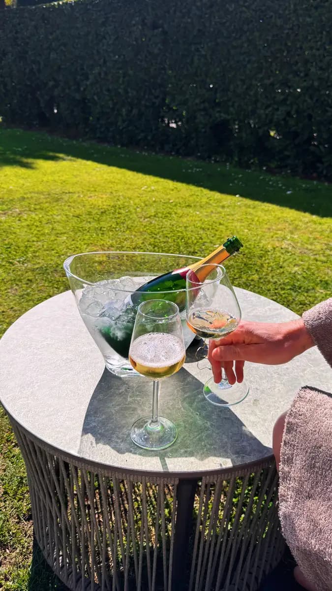 bottle of champage on a table outside with a bucket of ice
