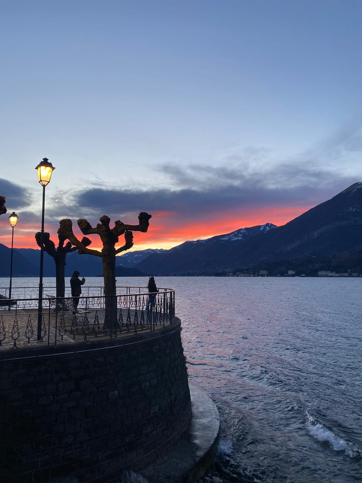 Golden hour sunset views along the lakefront promenade in front of an old hotel in Bellagio, Lake Como.
